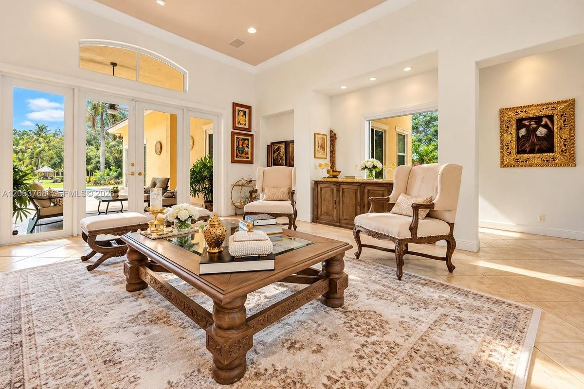 Living space featuring high ceilings, recessed lighting, tile flooring, an arched transom window, and multi-panel glass doors
