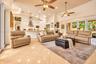 Open-concept interior featuring tray ceilings, neutral tile flooring, multiple ceiling fans with integrated lighting, recessed lighting, and sliding g