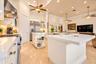 Kitchen featuring white cabinetry, solid-surface countertops, a center island with built-in shelving, stainless steel appliances, and tile flooring