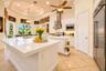 Kitchen featuring a tray ceiling, expansive stone-surfaced center island, stainless steel appliances, white cabinetry, and recessed lighting