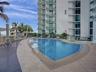 Swimming pool featuring a stone-tile deck, integrated metal handrails, and a built-in shade structure