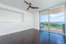 Dark wood-finish flooring, recessed wall niche, modern blade-style ceiling fan, and floor-to-ceiling sliding glass doors opening to a private balcony 