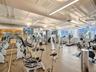 Fitness center featuring industrial-style exposed ductwork, wall-to-wall mirrored surfaces, expansive windows, linear overhead lighting, and stone-fin
