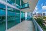 Covered balcony featuring oversized tile flooring, full-height glass sliding doors, and a glass-paneled railing