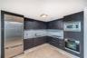 Kitchen featuring dark-toned flat-panel cabinetry, stone countertops, integrated stainless steel refrigerator, built-in microwave, and wall-mounted ov