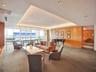 Expansive living area featuring a tray ceiling with integrated recessed lighting, floor-to-ceiling windows, and wood-paneled walls