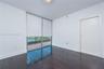 Room featuring dark wood-finish flooring, floor-to-ceiling windows, and access to a balcony with water scenery