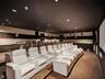 Dedicated media room featuring tiered platform flooring, integrated ceiling recessed lighting, wall-mounted speakers, and large-format projection scre