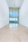 Double-height ceilings, floor-to-ceiling glass wall, polished stone flooring, and ceiling-mounted fan, overlooking water and city skyline