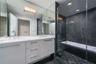 Bathroom featuring white cabinetry, stone-finish vanity countertop, dual undermount sinks with polished chrome fixtures, full-height vanity mirror, an