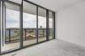 Floor-to-ceiling glass panel walls, polished concrete flooring, and private balcony with black metal railing