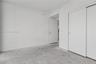 Minimalist interior featuring smooth white walls, sliding closet doors, a solid-core swing door, and concrete flooring