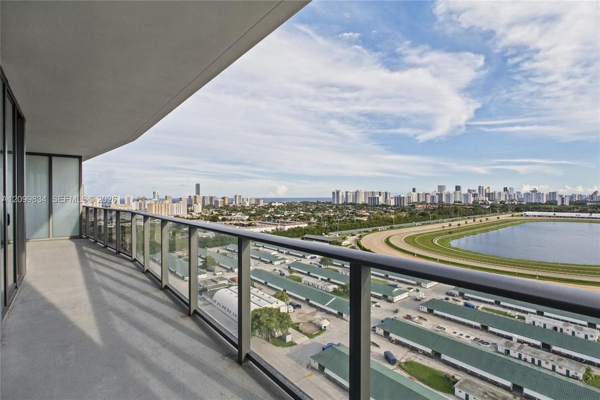 Covered balcony featuring concrete flooring and a glass-paneled railing with a dark metal frame