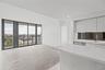 Kitchen featuring high-gloss cabinetry, white solid-surface countertops, and a dark mirrored backsplash, complemented by expansive floor-to-ceiling wi