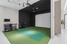 Dedicated simulation room featuring synthetic turf flooring, floor-to-ceiling acoustic wall panels, an integrated projection screen, and overhead trac