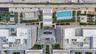 Aerial perspective featuring a central swimming pool, landscaped palm tree courtyards, paved pedestrian walkways, and structured surface parking