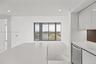 Kitchen featuring high-gloss white cabinetry, white stone countertops, built-in stainless steel dishwasher, recessed lighting, and floor-to-ceiling gl