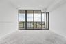 Floor-to-ceiling windows featuring black framing, sliding glass door, and a private balcony with metal railing