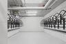 Dedicated storage room featuring wall-mounted metal bicycle racks, concrete flooring, and linear fluorescent lighting