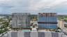 Aerial perspective of two high-rise towers featuring glass-paneled facades, integrated balconies, a ground-level swimming pool, and structured parking