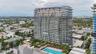 High-rise residential building featuring floor-to-ceiling glass windows, private balconies, a ground-level swimming pool, and dedicated cabana structu