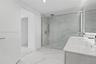 Bathroom featuring a dual-sink vanity with a white solid-surface countertop, walk-in shower with floor-to-ceiling stone-finish tile, glass shower encl