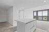 Kitchen island with a white countertop and flat-panel cabinetry, floor-to-ceiling glass sliding doors, and balcony with metal railing