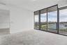 Floor-to-ceiling windows with dark metal framing, concrete flooring, and access to a balcony with metallic railing