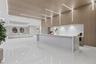 Expansive interior featuring large-format tile flooring, integrated linear LED lighting, natural wood-finish wall and ceiling paneling, and a stone-su
