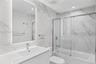 Bathroom featuring floor-to-ceiling large-format stone-finish tile, a backlit mirror, a vanity with a rectangular basin, and a glass-enclosed shower-t