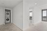 Stacked laundry unit enclosed in a louvered-door closet featuring white walls, recessed ceiling lighting, and floor-to-ceiling windows
