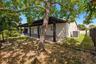 Stucco exterior side yard featuring a covered patio with tile flooring, enclosed by a dark wood privacy fence