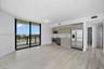 Open-concept living space featuring wood-finish flooring, floor-to-ceiling glass sliding doors, horizontal wood-grain cabinetry, stainless steel appli