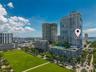 Vibrant urban skyline featuring modern high-rise residential towers with glass and metal facades, manicured green space with mature landscaping, tree-