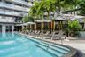 Resort-style pool deck featuring a sparkling lap pool with lane dividers, multiple white umbrellas with integrated shade structures, lounge seating, l