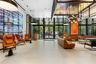 Floor-to-ceiling glass entry doors, large-format tile flooring, industrial-style multi-pendant lighting, recessed ceiling fixtures, and expansive wall