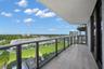 Covered balcony featuring wood-finish tile flooring and a glass-panel railing with metal frame