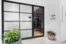 Black metal-framed glass partition with frosted panels and matching entry door featuring clear glass insets