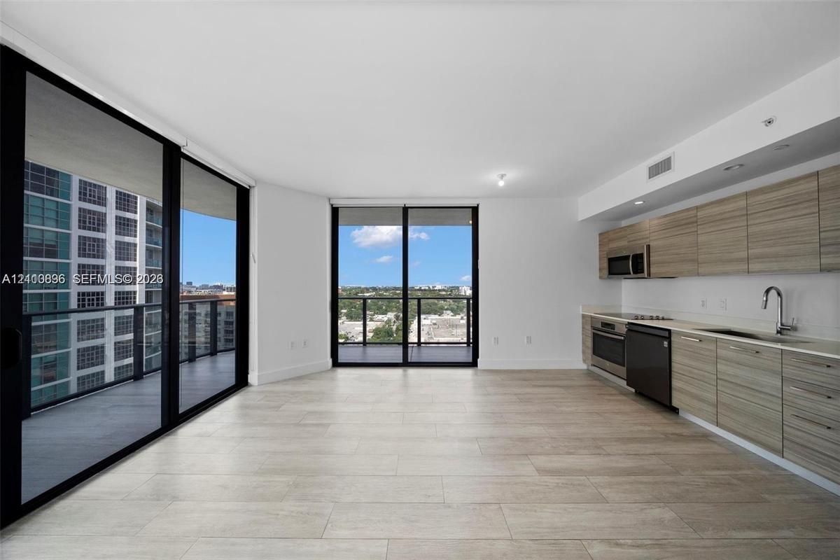 Modern kitchen featuring wood-finish cabinetry, stainless steel appliances, and integrated faucet fixtures, complemented by tile flooring and floor-to