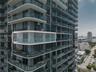 Modern high-rise residential tower featuring curved glass balconies, floor-to-ceiling windows, and streamlined white architectural trim