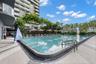 Resort-style lagoon pool with turquoise water and curved architectural design, framed by mature palm trees and lush landscaping