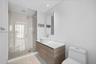 Bathroom featuring a wood-finish floating vanity, circular vessel sink, white solid-surface countertop, and a walk-in glass-enclosed shower with polis
