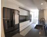 Modern kitchen featuring high-gloss white flat-panel cabinetry, dark solid-surface countertops, built-in stainless steel oven, integrated cooktop, and