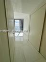 Hallway featuring large-format light-toned flooring, minimalist door frames, and floor-to-ceiling glass paneling