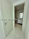 Solid-core white interior door with a contemporary metallic handle, polished tile flooring, wall-mounted floating vanity with integrated basin, and il