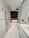Freestanding soaking tub, glass-enclosed shower, wall-mounted vanity with integrated sink, and polished large-format tile flooring