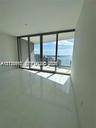 Floor-to-ceiling sliding glass doors, polished stone tile flooring, recessed ceiling lighting, and expansive water scenery