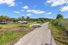 Expansive parcel featuring mature palm trees and chain-link perimeter fencing