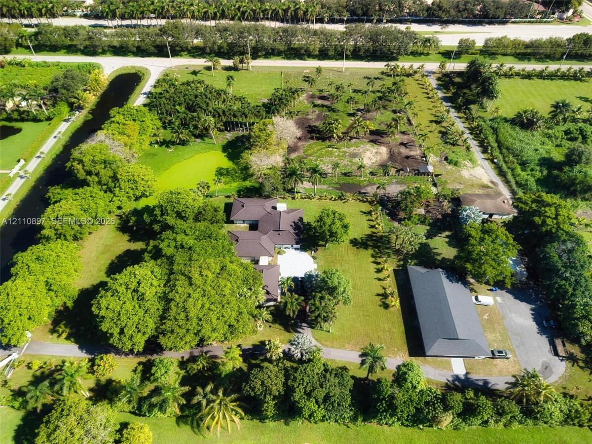 Expansive acreage featuring a multi-structure layout, mature trees, manicured lawns, and private paved driveways