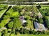Expansive acreage featuring a multi-structure layout, mature trees, manicured lawns, and private paved driveways